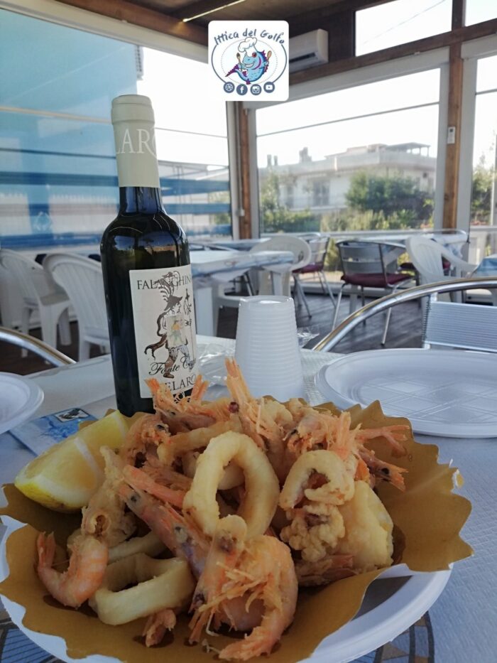 Gazebo Ittica del Golfo, con tavoli e sedie e sul tavolo frittura di calamari e bottiglia di bianco